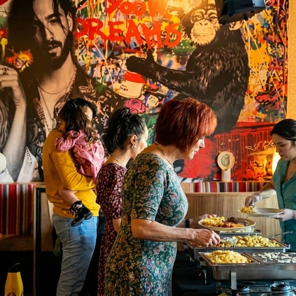 People serving themselves from a buffet line in a vibrant restaurant with pop art murals.